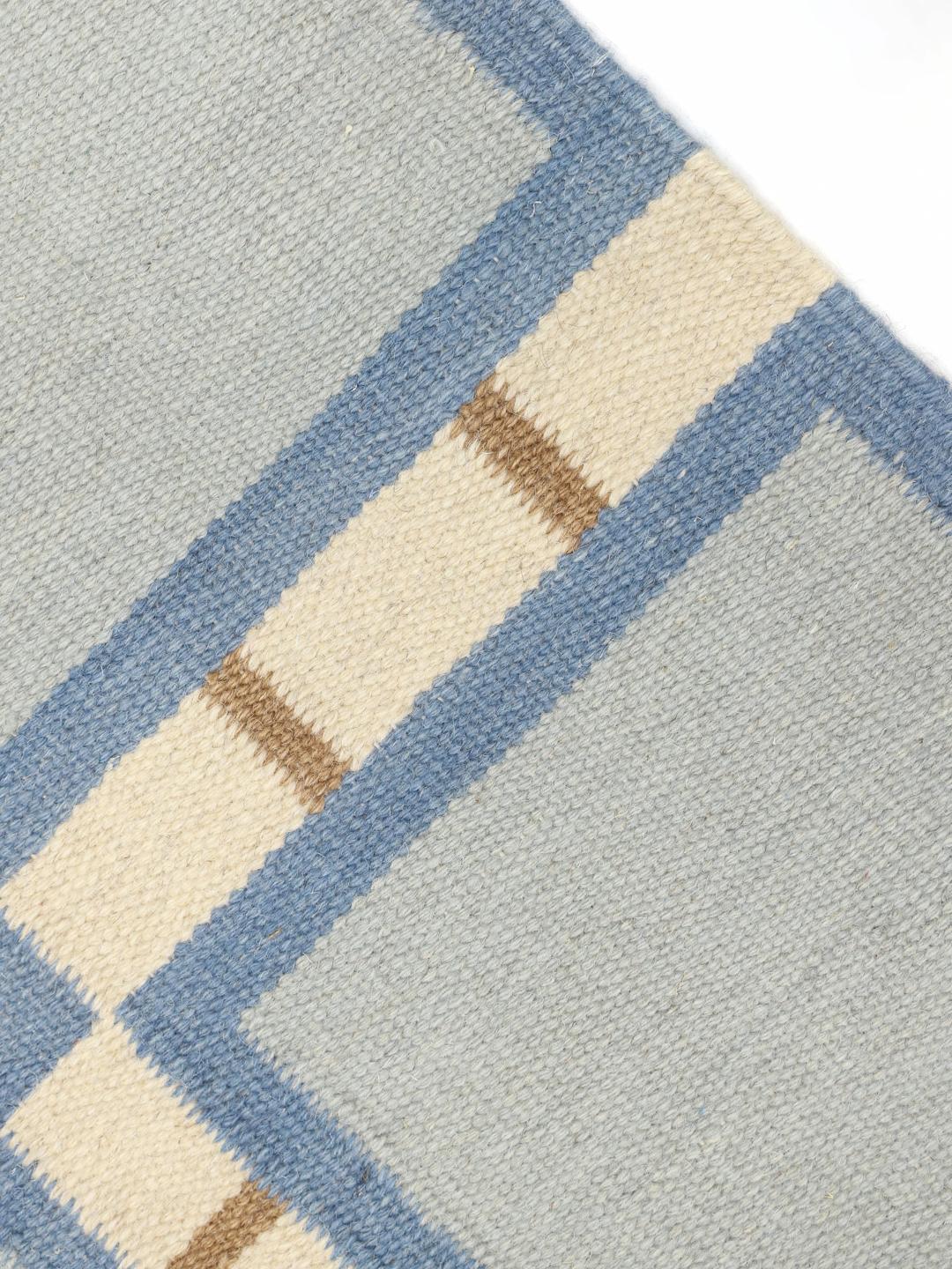 Un tapis rectangulaire en Wool avec un motif géométrique en grille bleu, beige et blanc.