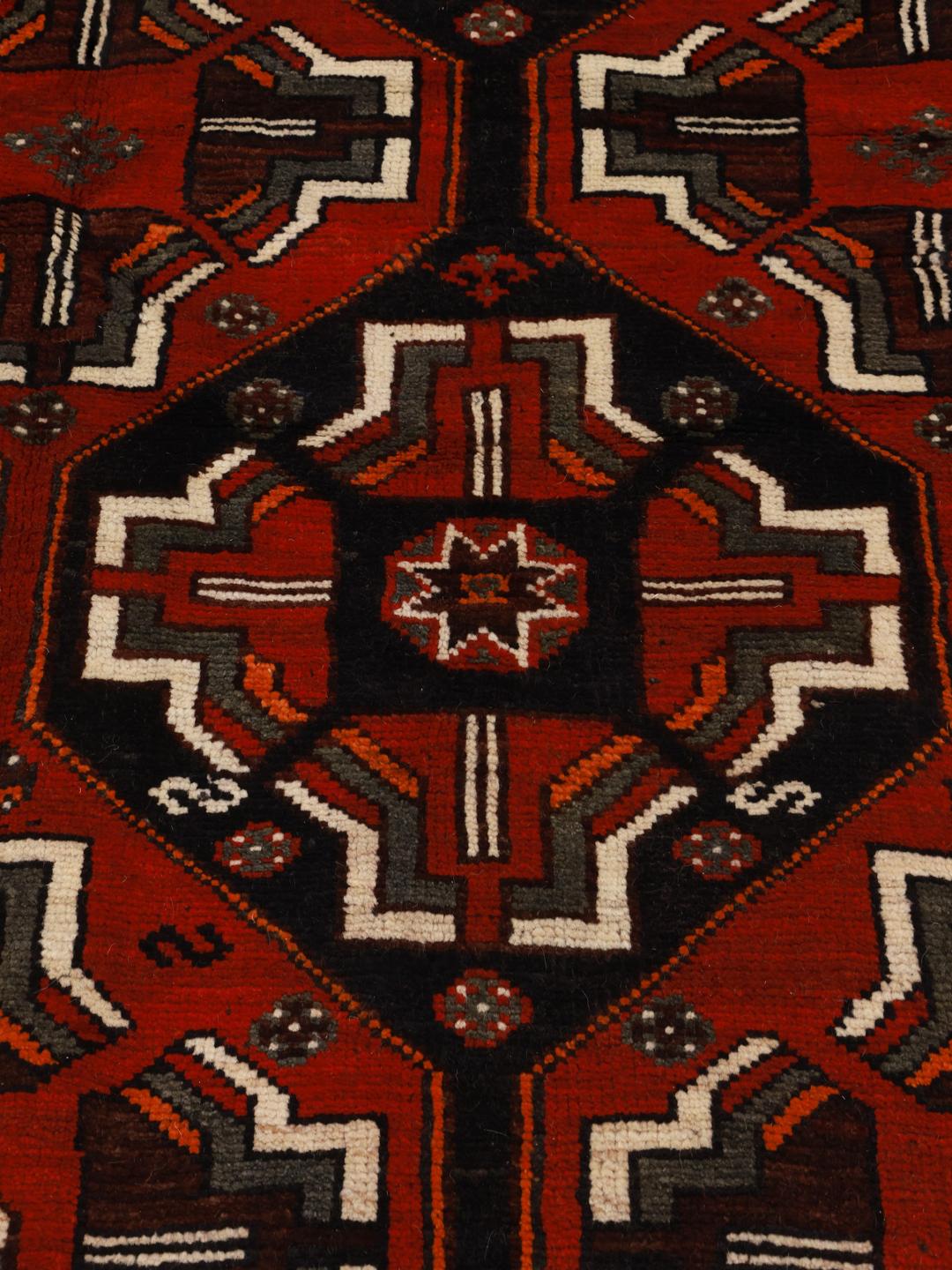 A hand-knotted Shiraz rug from the Middle East in deep red and black tones with geometric patterns.