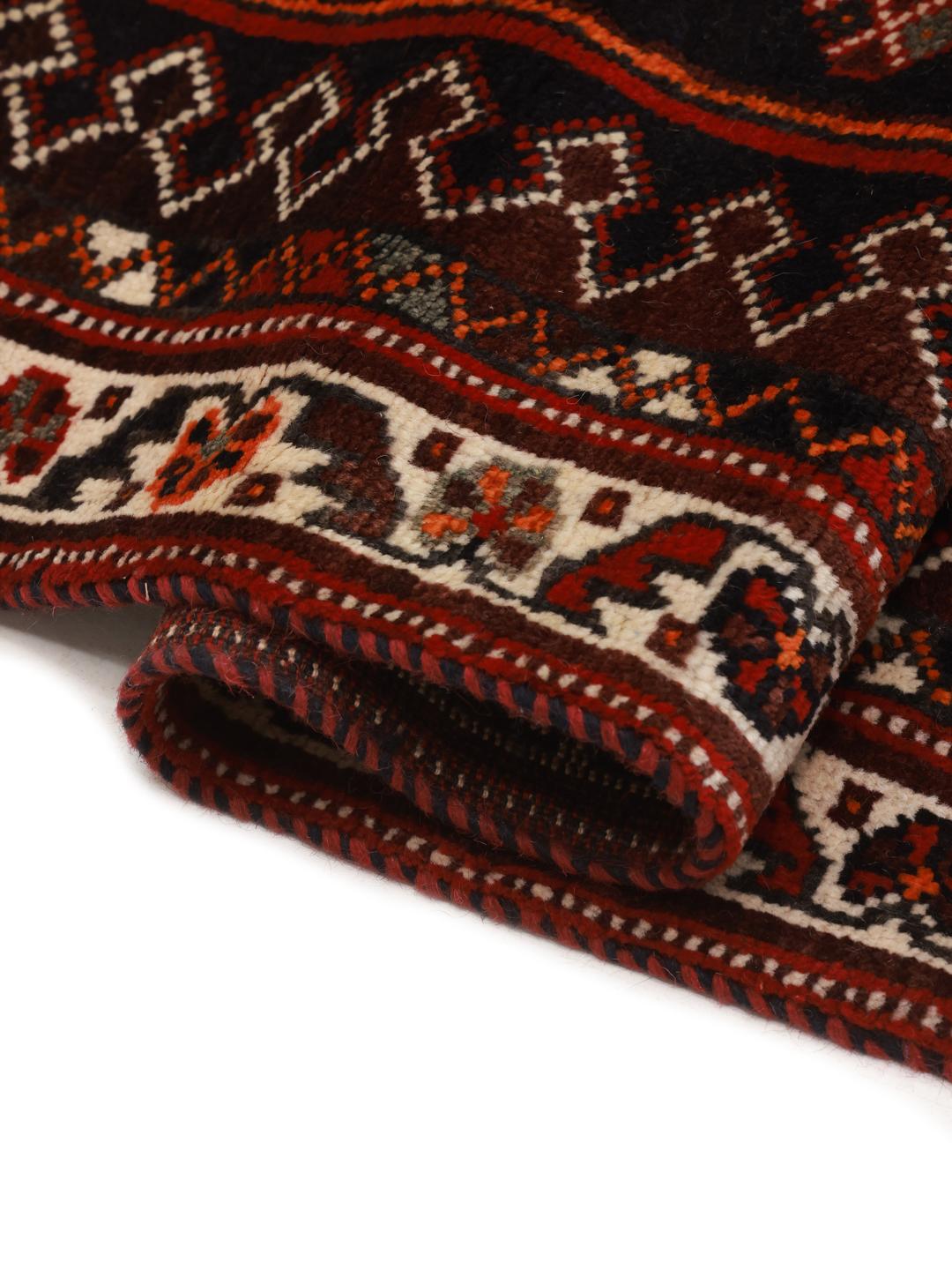 A hand-knotted Shiraz rug from the Middle East in deep red and black tones with geometric patterns.