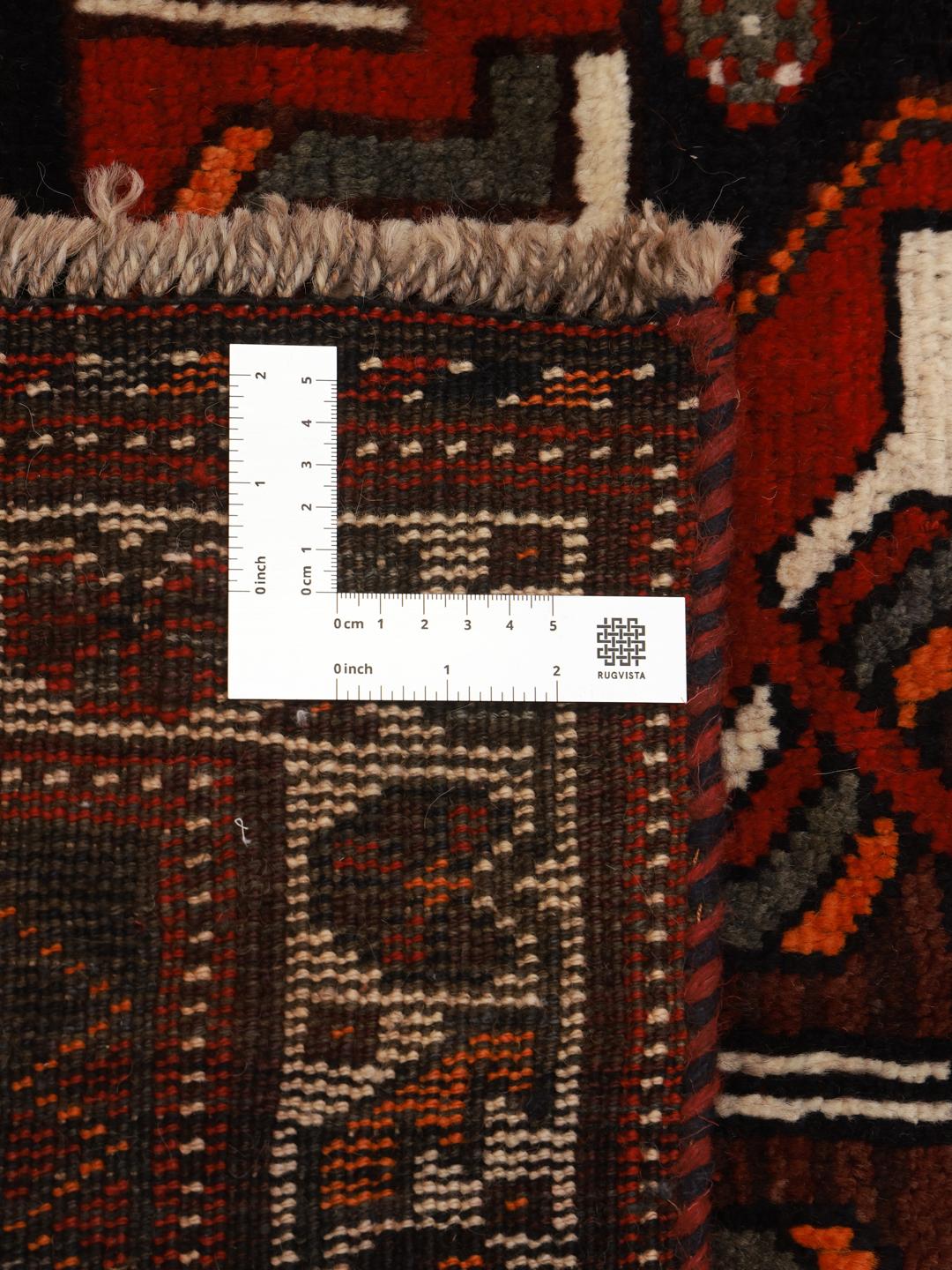 A hand-knotted Shiraz rug from the Middle East in deep red and black tones with geometric patterns.