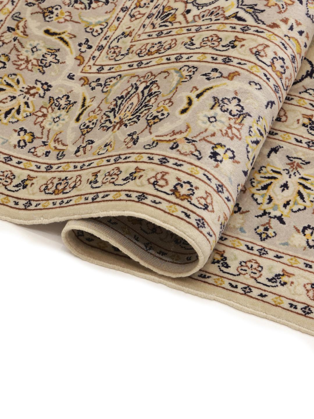 A hand-knotted Keshan rug from the Middle East featuring a beige field with floral patterns.
