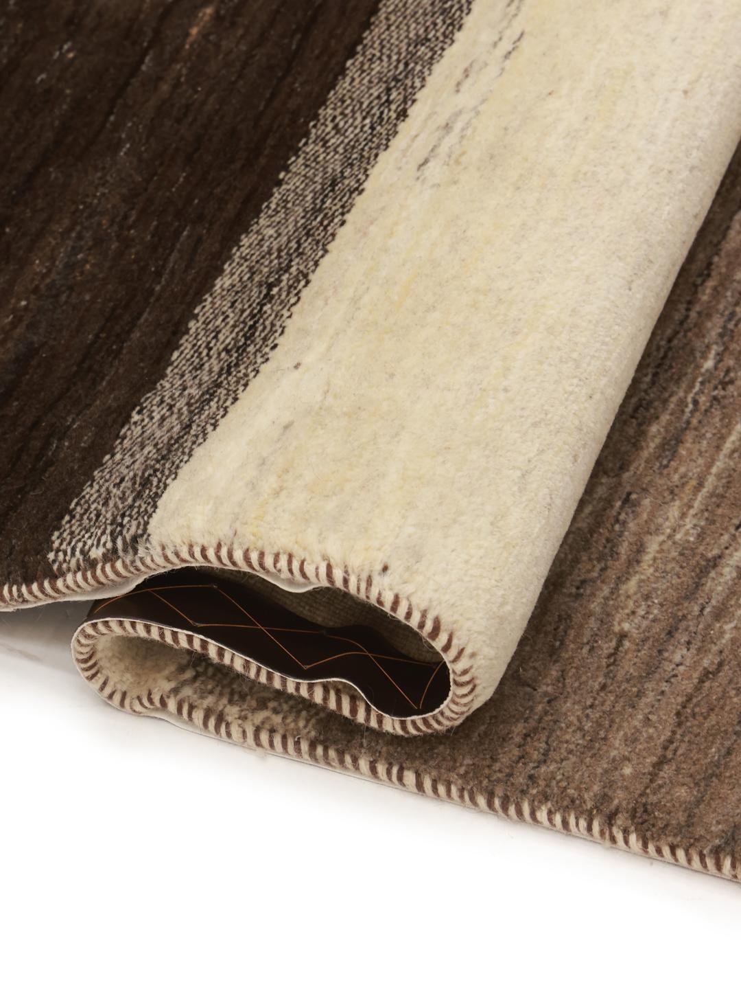A hand-knotted Gabbeh rug from the Middle East featuring striped earthy brown and beige tones.