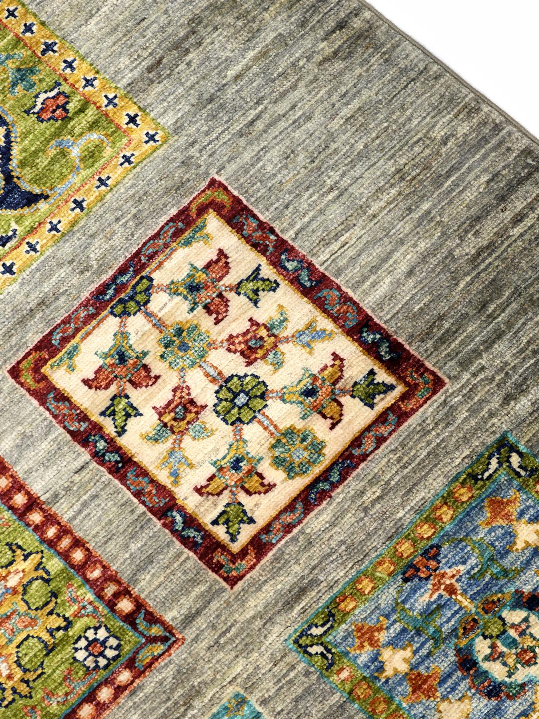 Handgeknoopt Afghaans kleed met kleurrijke motieven op een grijze achtergrond