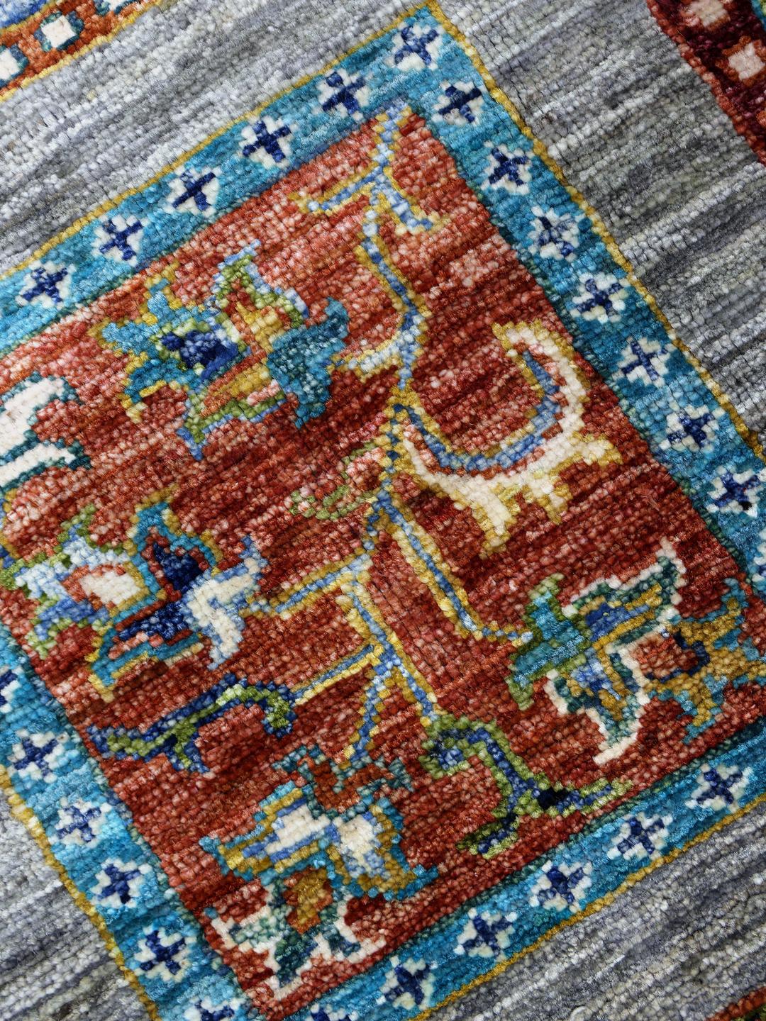 Handgeknoopt Afghaans kleed met kleurrijke motieven op een grijze achtergrond