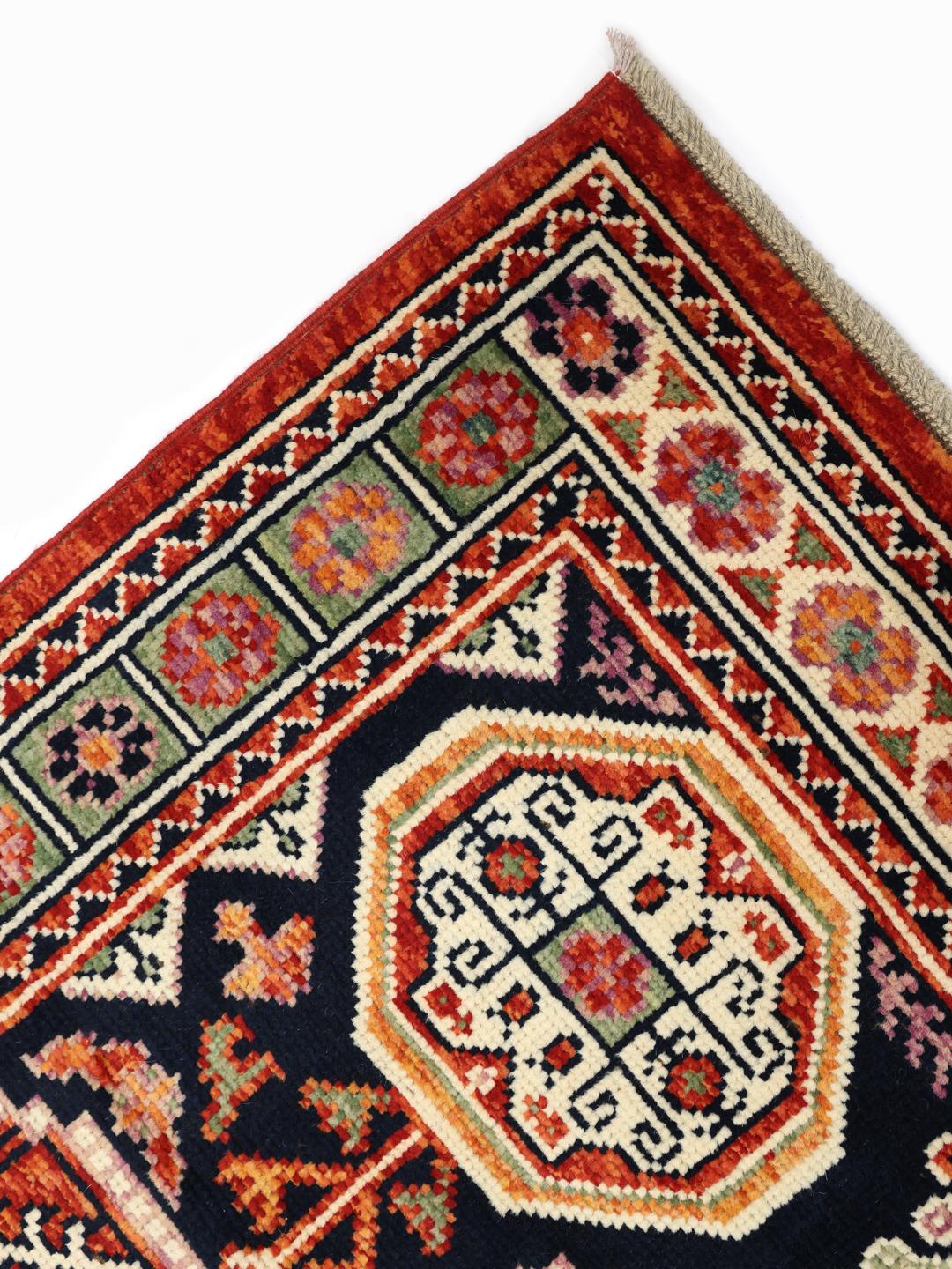 Un covor afgan Kazak înnodat manual, cu un câmp roșu închis și modele geometrice