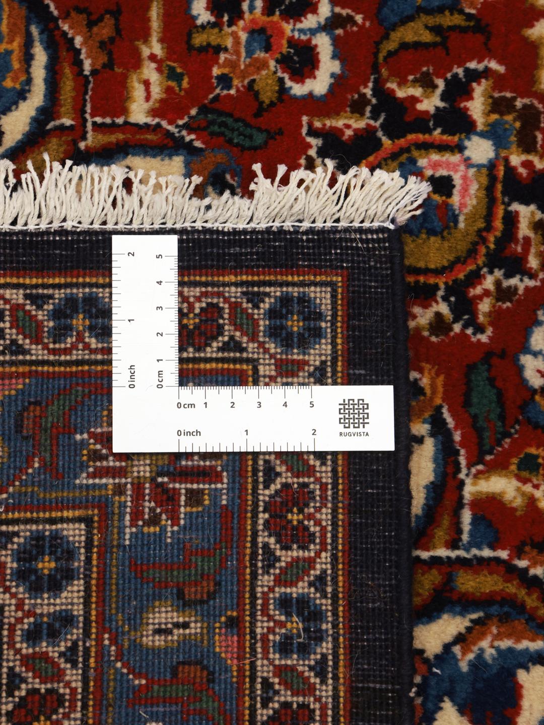 A large rectangular hand-knotted Keshan rug from the Middle East with a dark-blue and dark-red floral pattern.