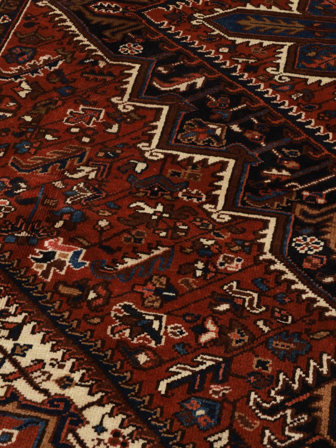 A hand-knotted Heriz rug from the Middle East featuring a vibrant red and blue geometric medallion design.