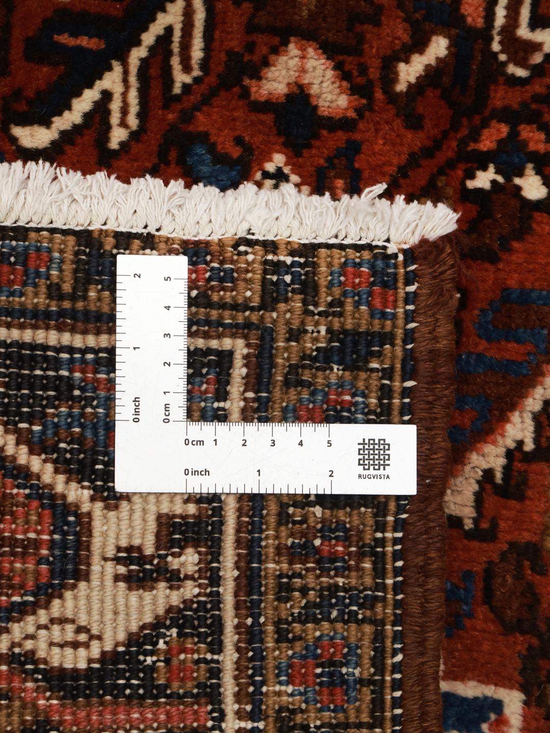 A hand-knotted Heriz rug from the Middle East featuring a vibrant red and blue geometric medallion design.