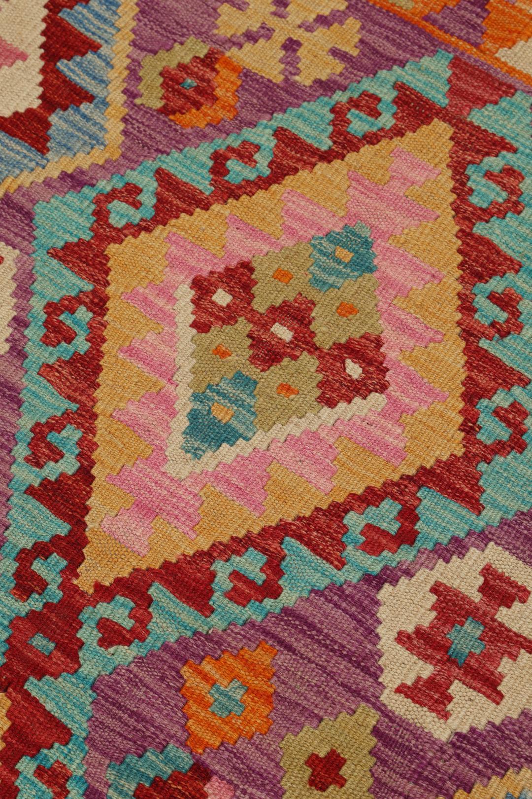 Hand-woven Afghan Kelim rug featuring geometric patterns in orange, purple, and blue.