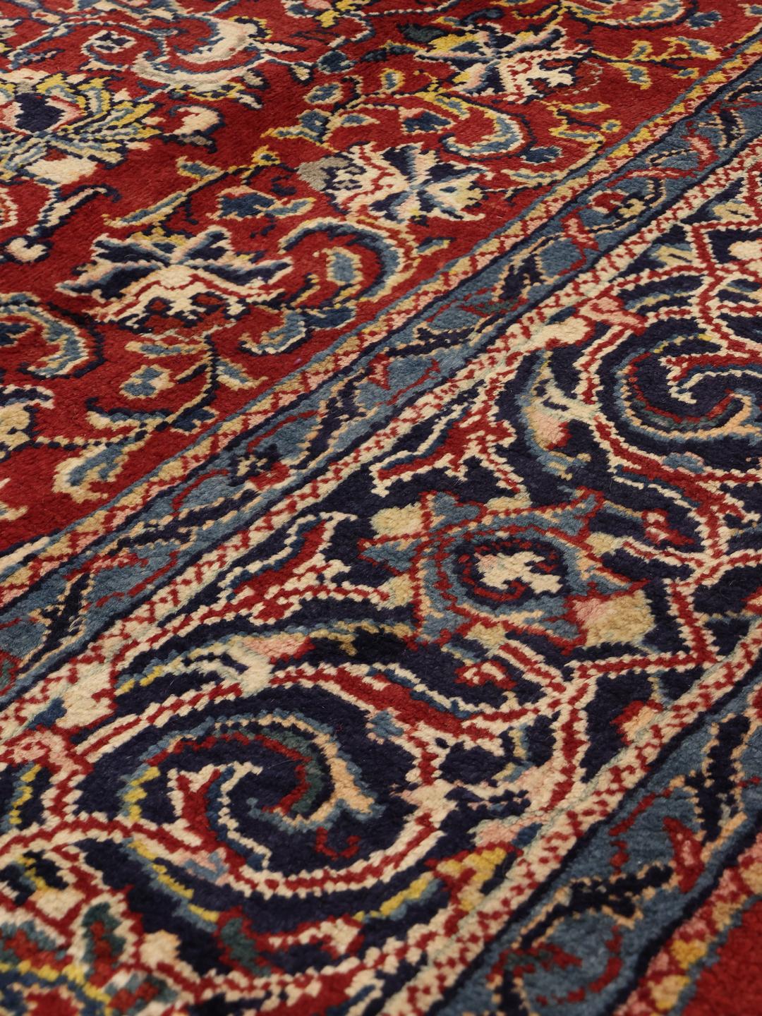 Een handgeknoopt Mahal-tapijt uit het Midden-Oosten met een donkerrood veld en verfijnde blauwe bloemmotieven.