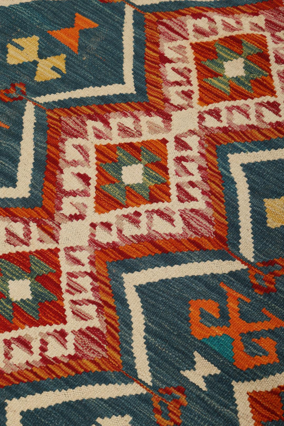 A rectangular, hand-woven Kelim Afghan rug featuring geometric patterns in blue, red, and orange tones.