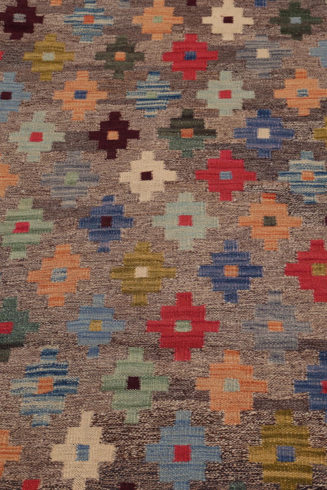 Hand-woven Afghan kelim rug with colourful geometric motifs on a grey background
