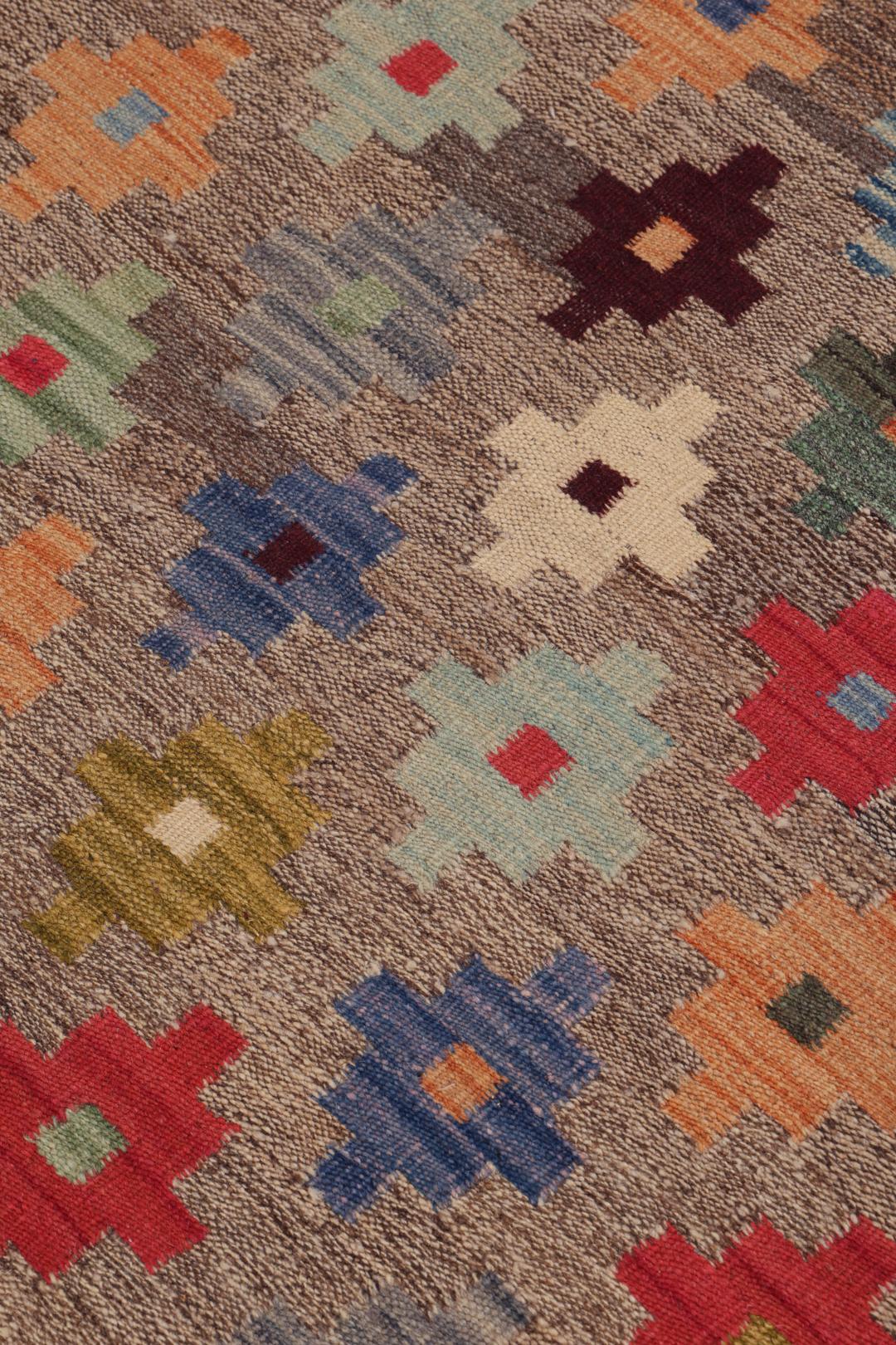 Hand-woven Afghan kelim rug with colourful geometric motifs on a grey background