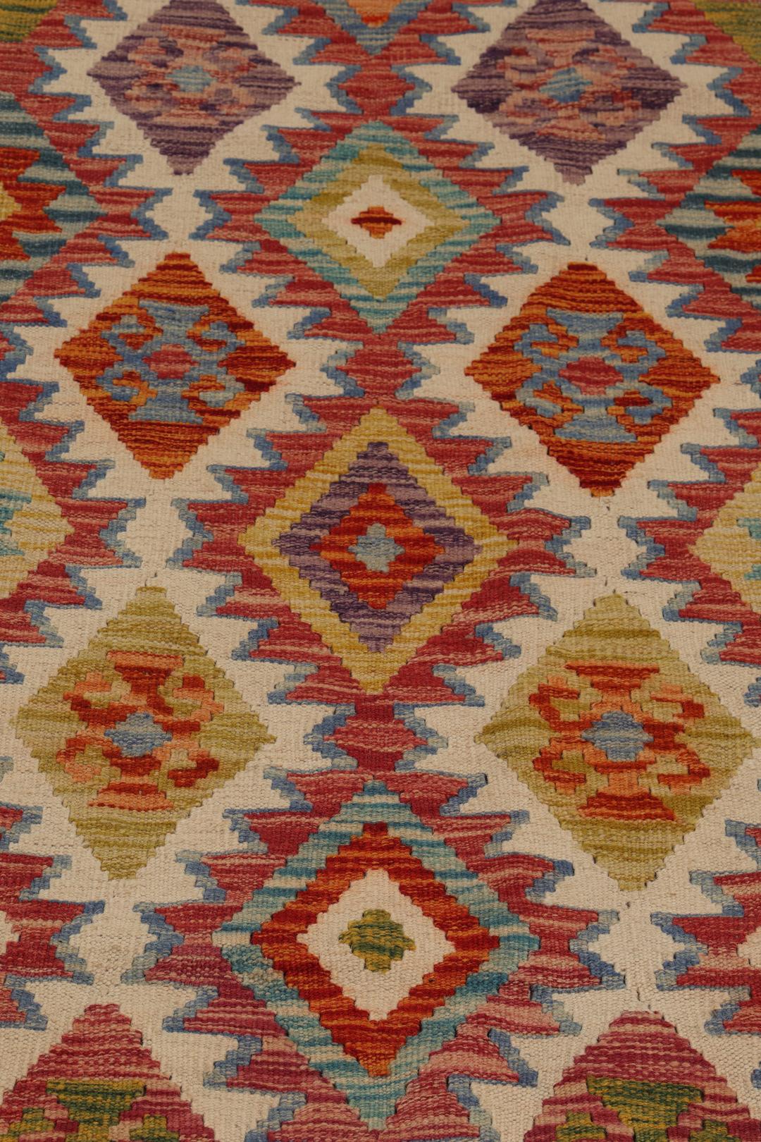 A hand-woven Afghan runner rug with a multicolor diamond pattern on a light background