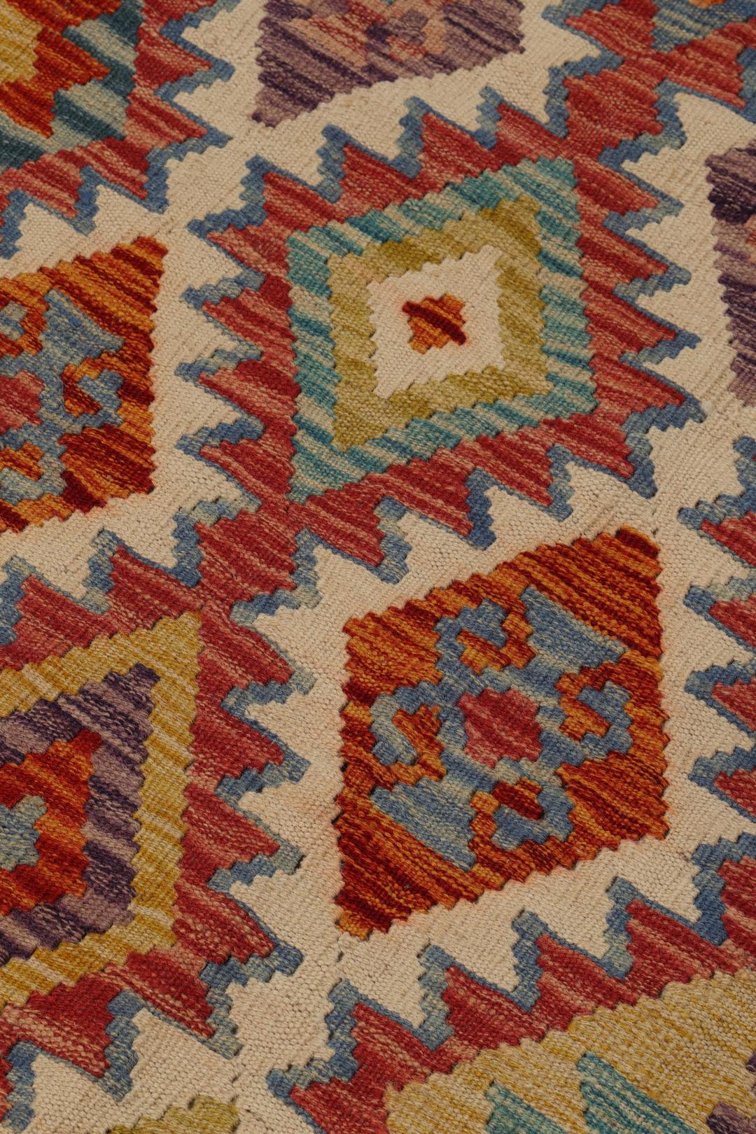 A hand-woven Afghan runner rug with a multicolor diamond pattern on a light background