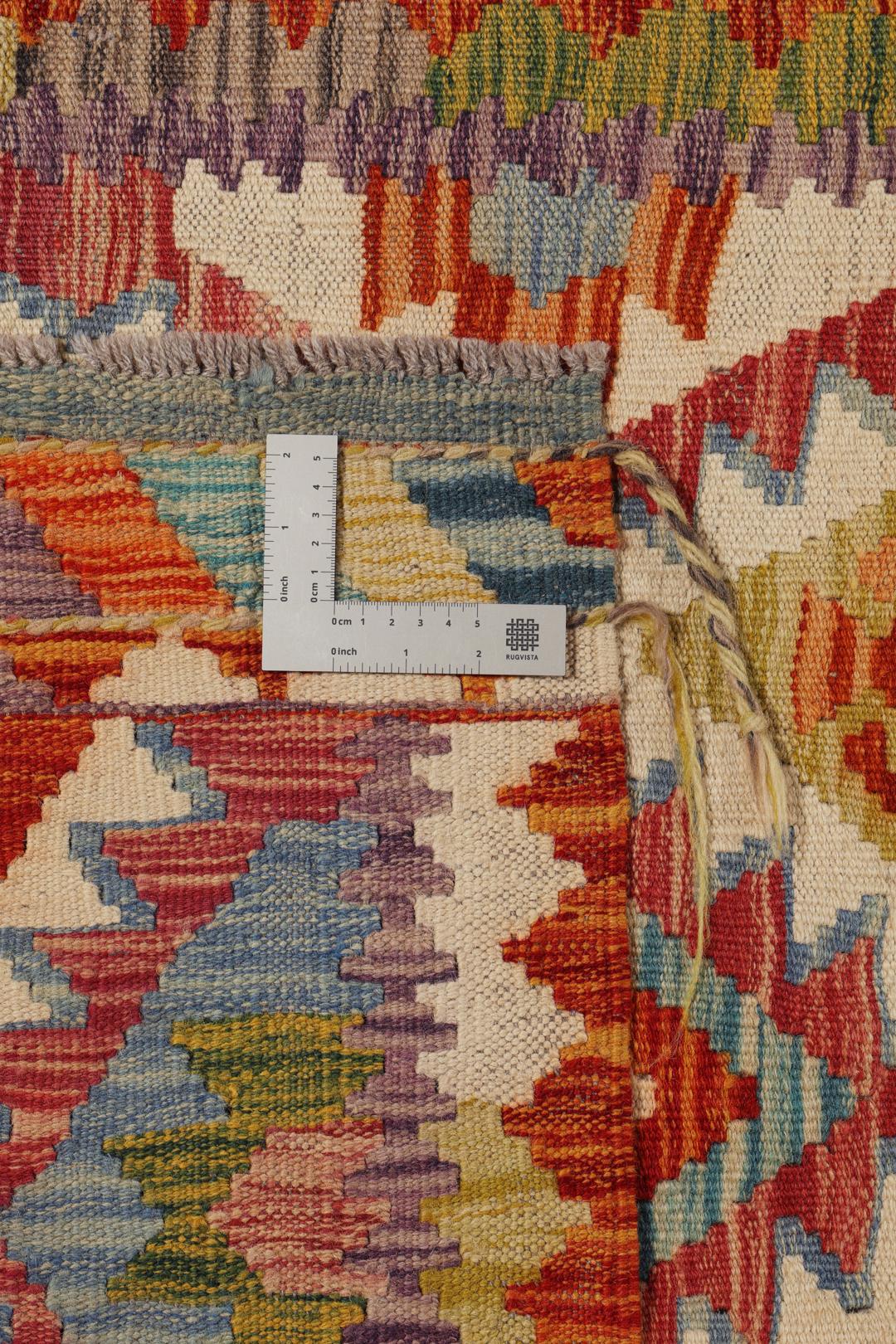 A hand-woven Afghan runner rug with a multicolor diamond pattern on a light background