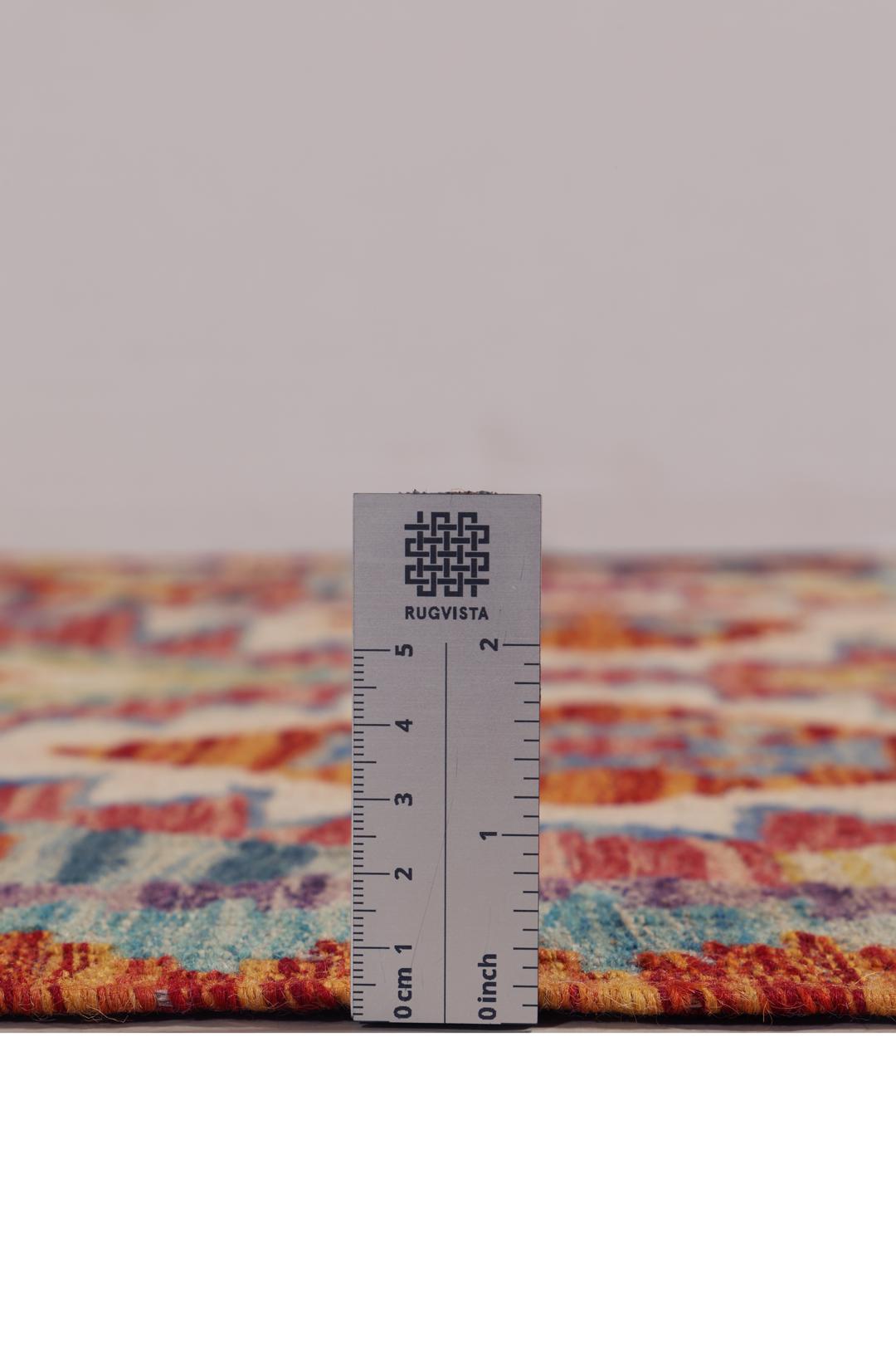 A hand-woven Afghan runner rug with a multicolor diamond pattern on a light background