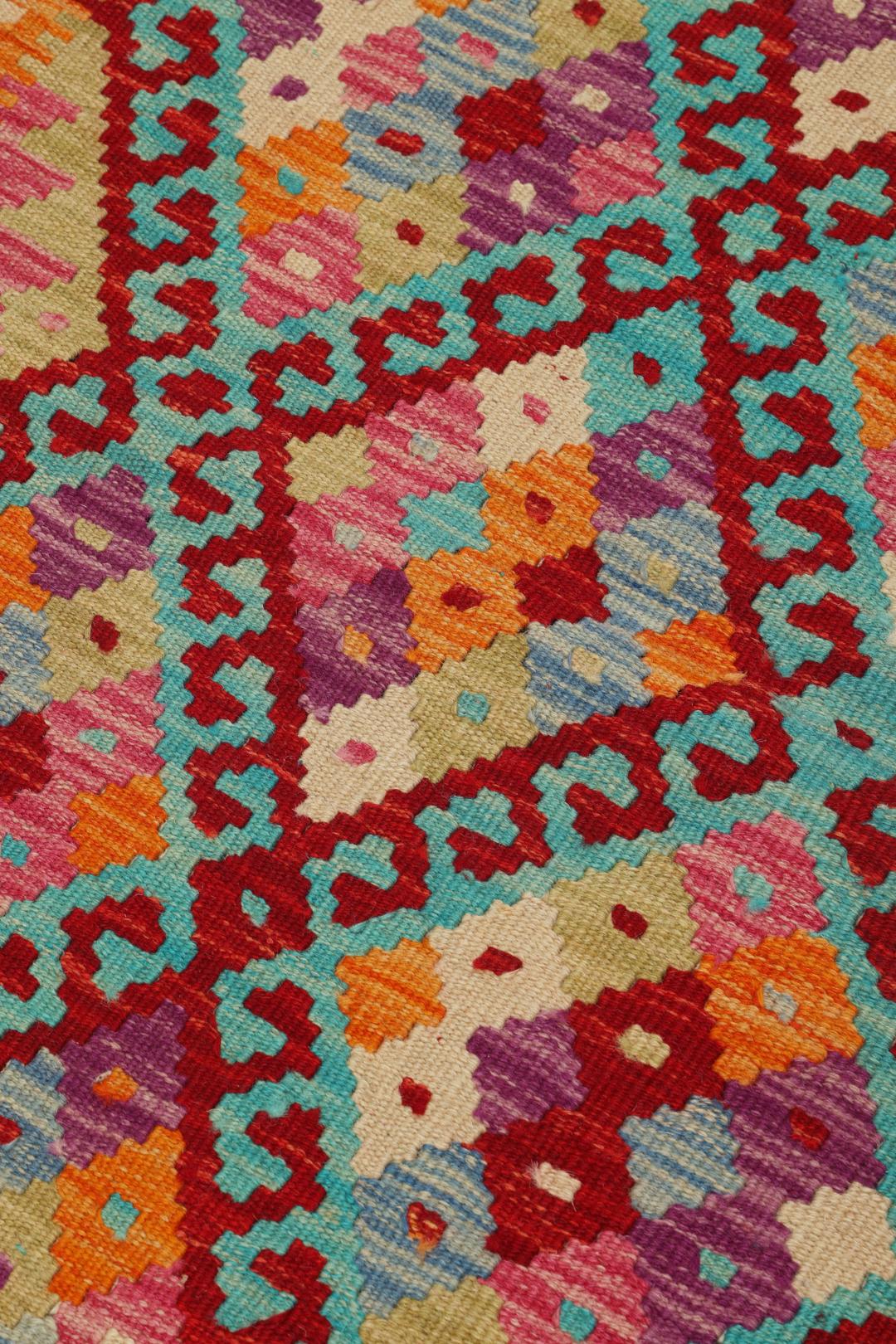 Hand-woven Afghan Kelim rug with vibrant geometric patterns in orange, teal, and purple