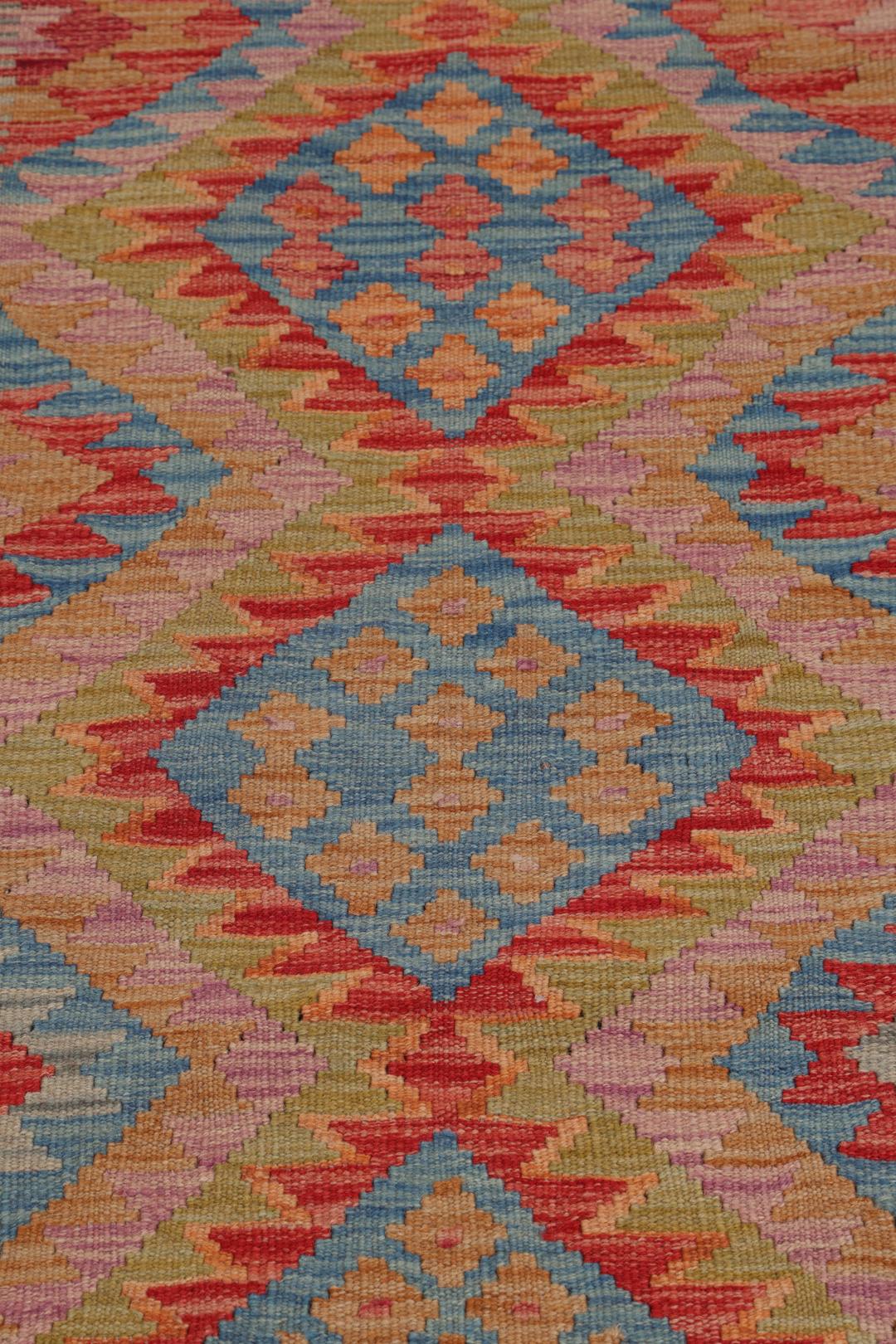 A hand-woven multicoloured Afghan runner with geometric diamond motifs.
