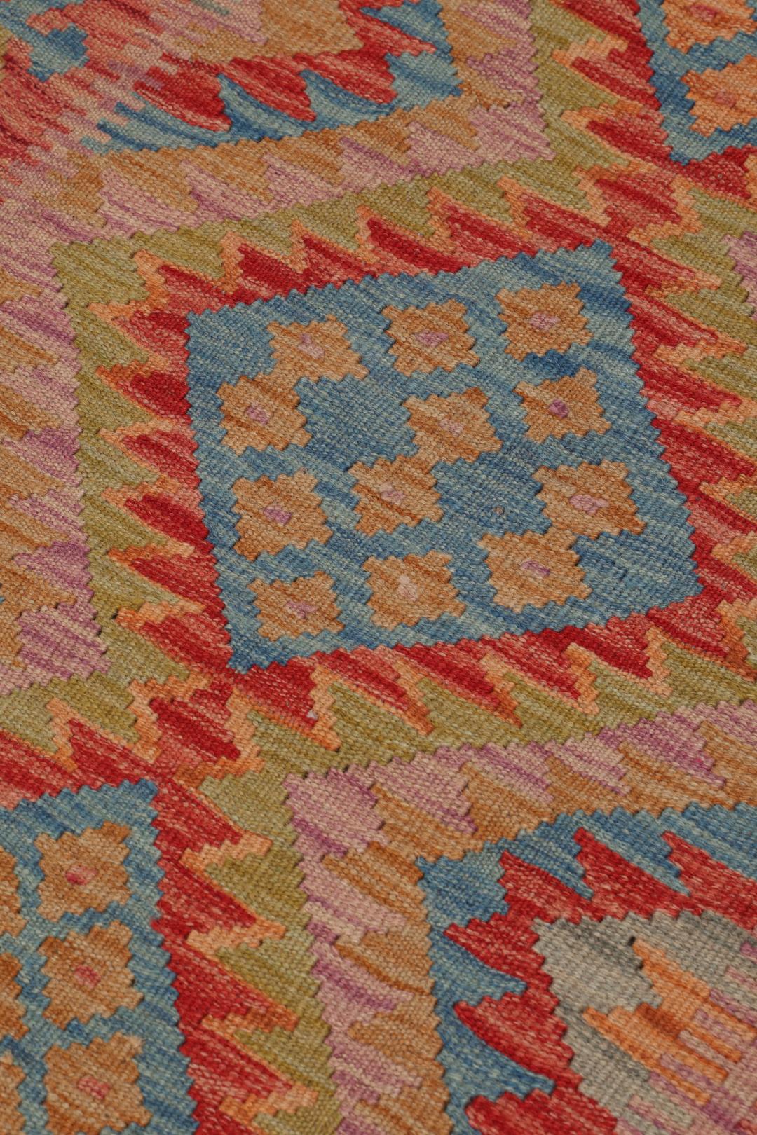 A hand-woven multicoloured Afghan runner with geometric diamond motifs.