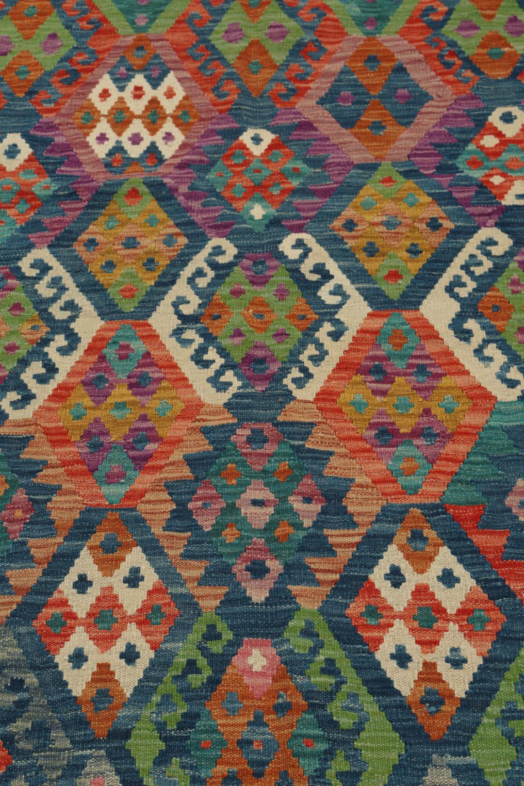 Hand-woven Afghan Kelim rug with a multicolor diamond pattern on a blue background
