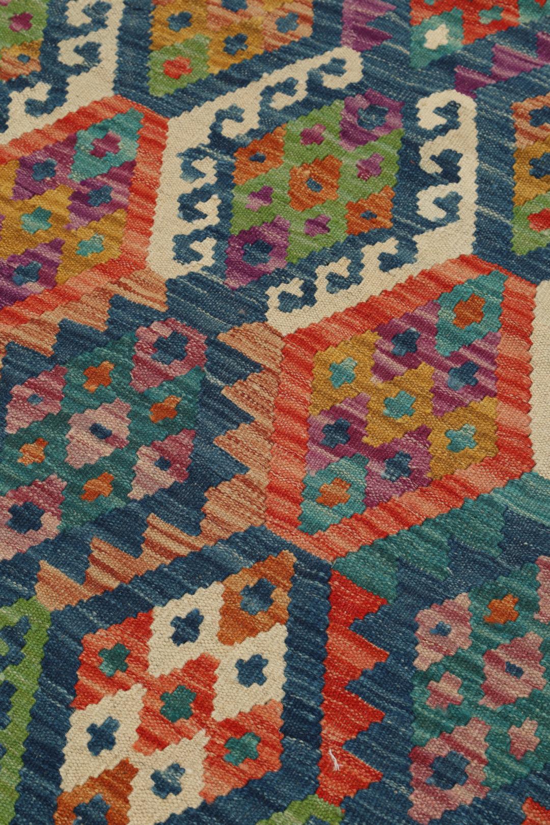 Hand-woven Afghan Kelim rug with a multicolor diamond pattern on a blue background