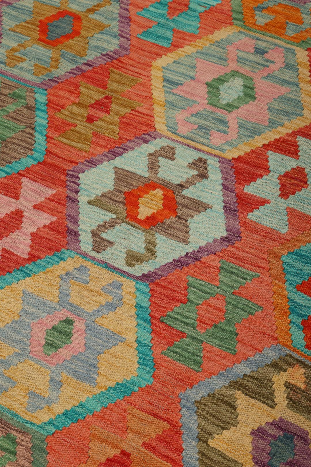 Handmade Kelim rug from Afghanistan with a colourful geometric pattern in red and multicolour tones.