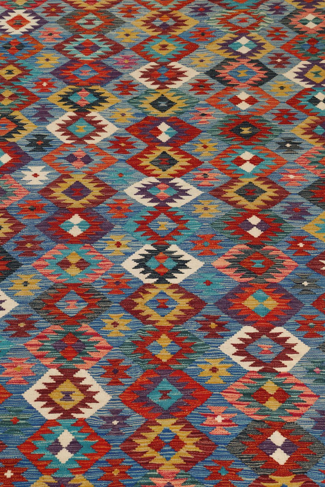 Een groot rechthoekig handgeweven Kelim-tapijt uit Afghanistan met een levendig, veelkleurig geometrisch patroon.
