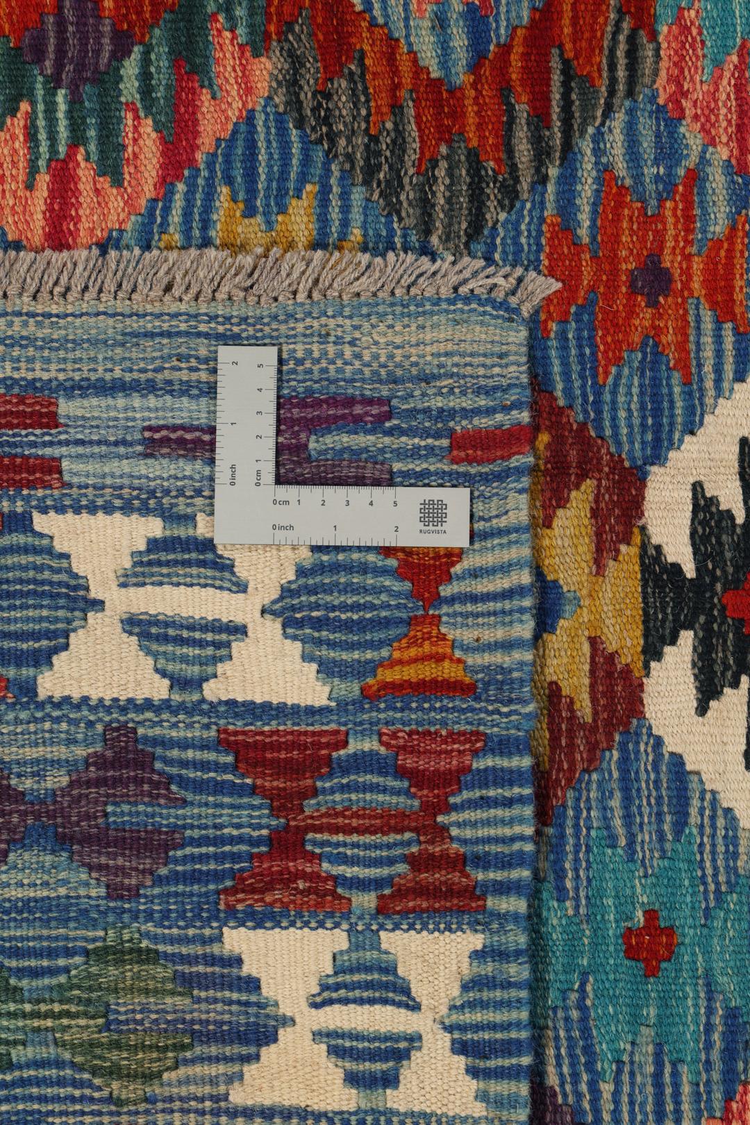 Een groot rechthoekig handgeweven Kelim-tapijt uit Afghanistan met een levendig, veelkleurig geometrisch patroon.