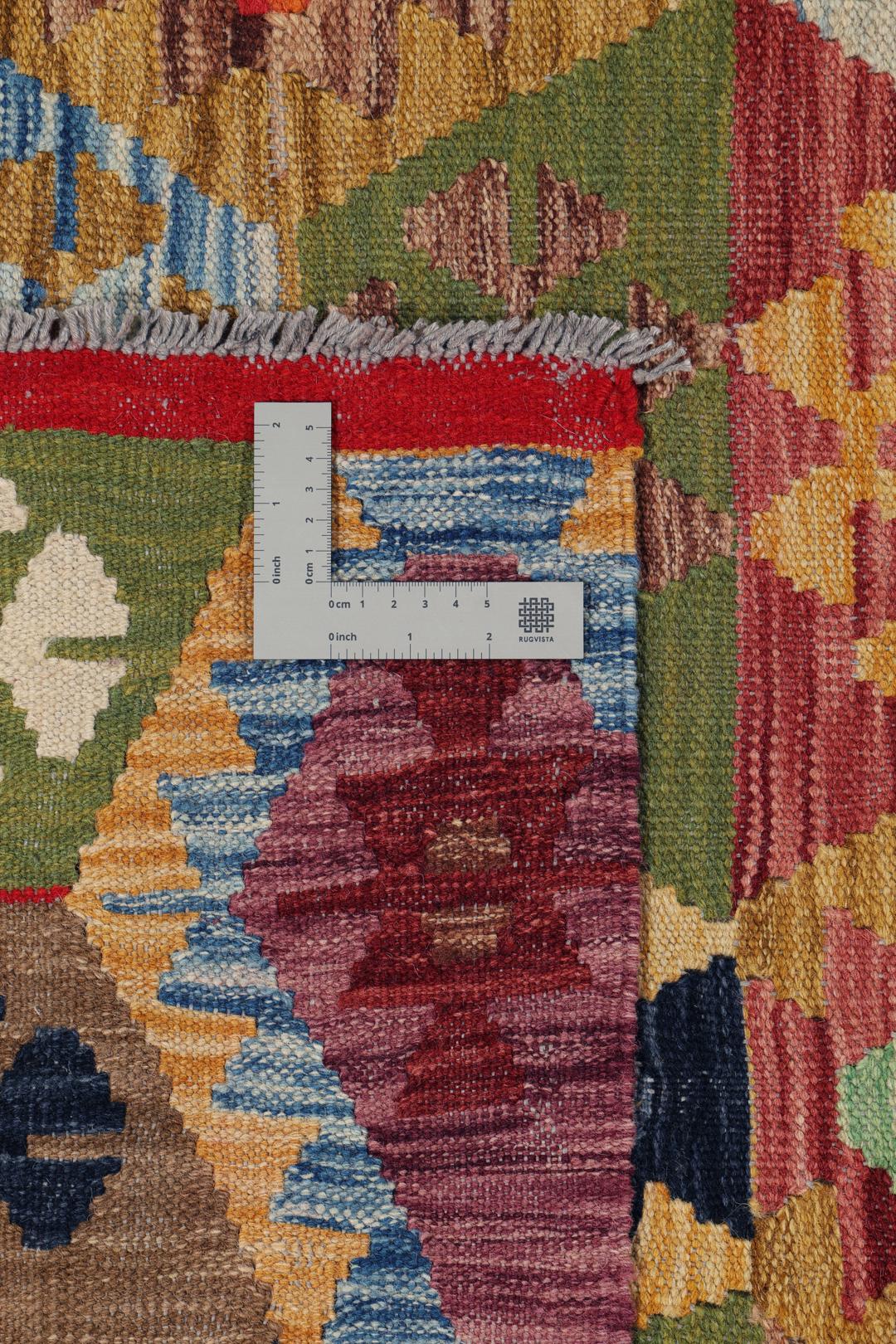 A large rectangular Afghan Kelim rug featuring a vibrant multicolor geometric pattern