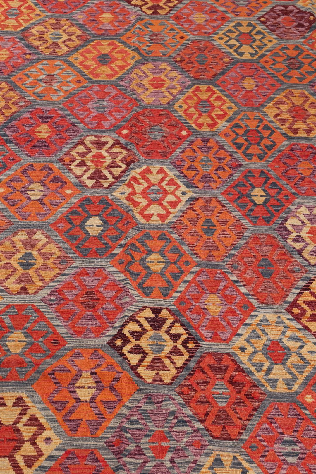 Håndvævet afghansk Kelim-tæppe med et levende geometrisk mønster i flerfarvede nuancer.