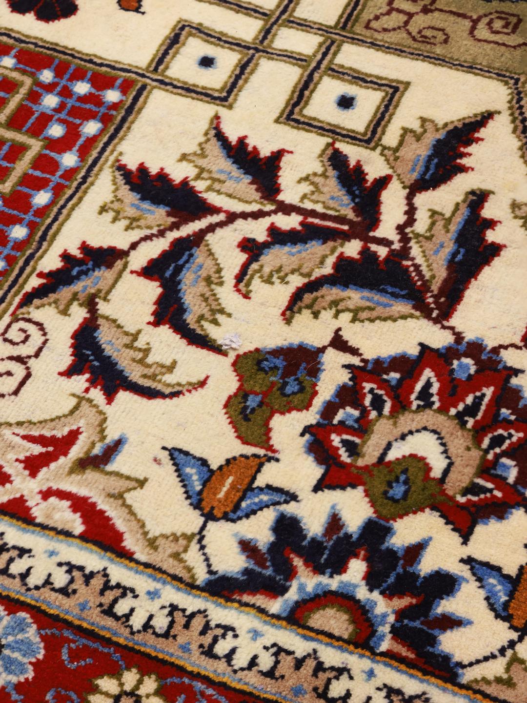Een handgeknoopt Najafabad-tapijt uit het Midden-Oosten in tinten beige, blauw en rood.