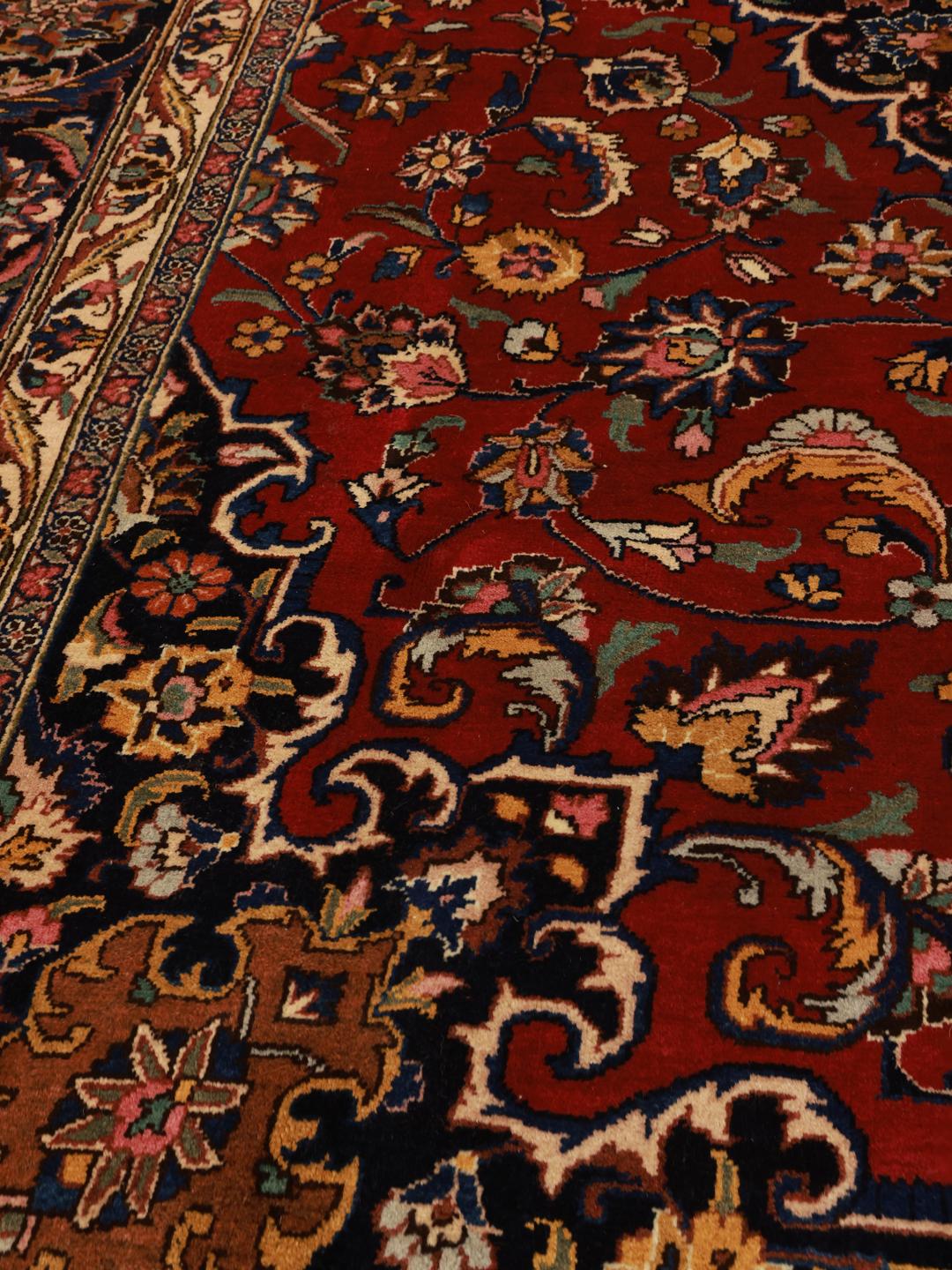 Een handgeknoopt Mashad-tapijt met een rood veld en verfijnde bloemmotieven in het medaillon.