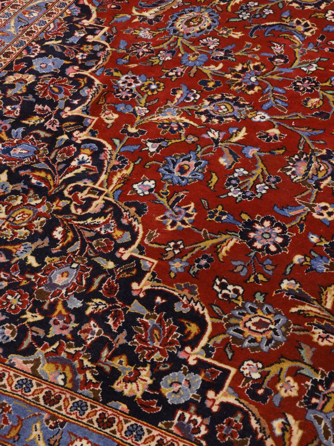 Een groot rechthoekig handgeknoopt Keshan-tapijt uit het Midden-Oosten met een rood veld en een ingewikkeld blauw en wit bloemenmedaillon.