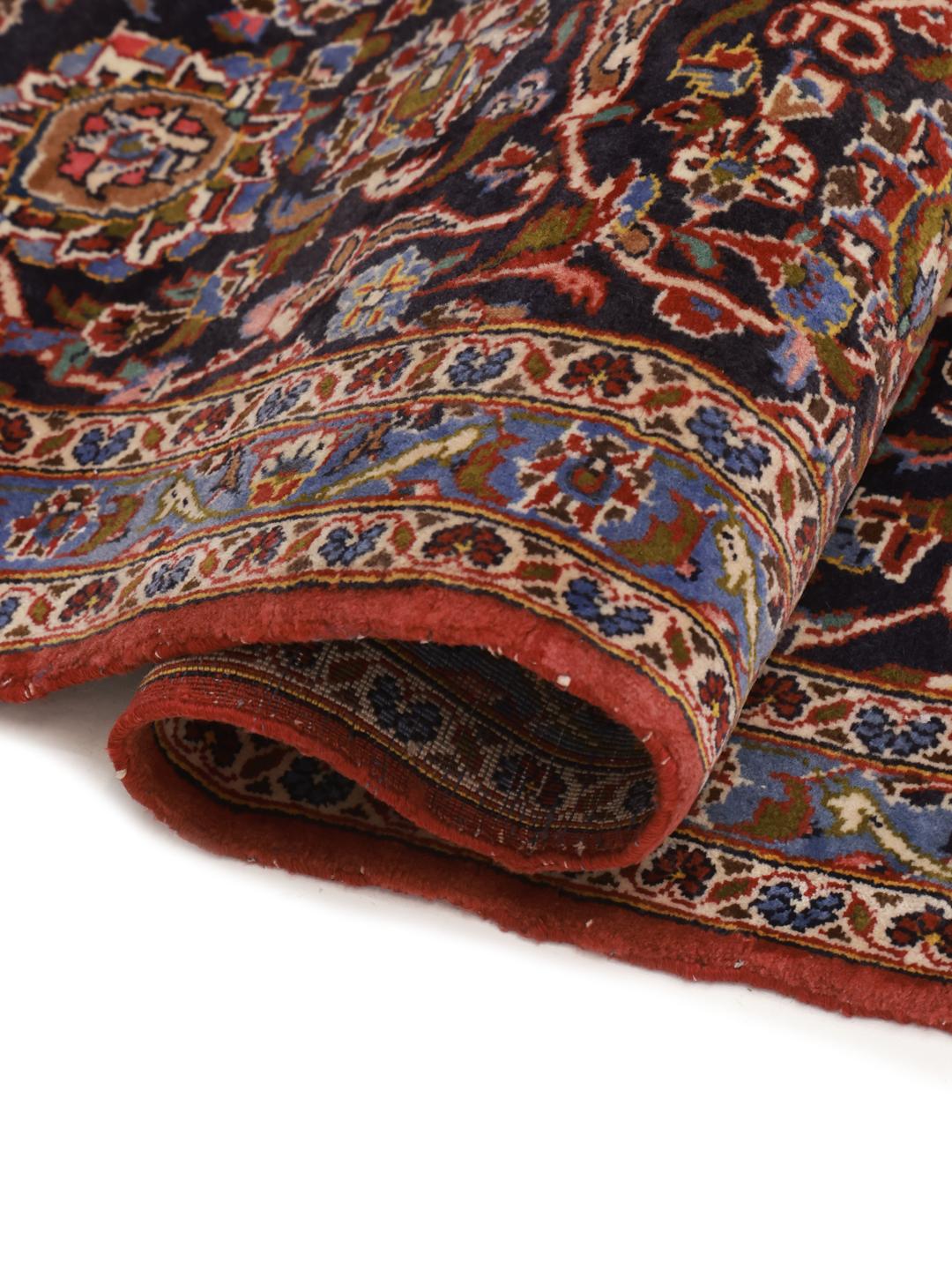 Een groot rechthoekig handgeknoopt Keshan-tapijt uit het Midden-Oosten met een rood veld en een ingewikkeld blauw en wit bloemenmedaillon.