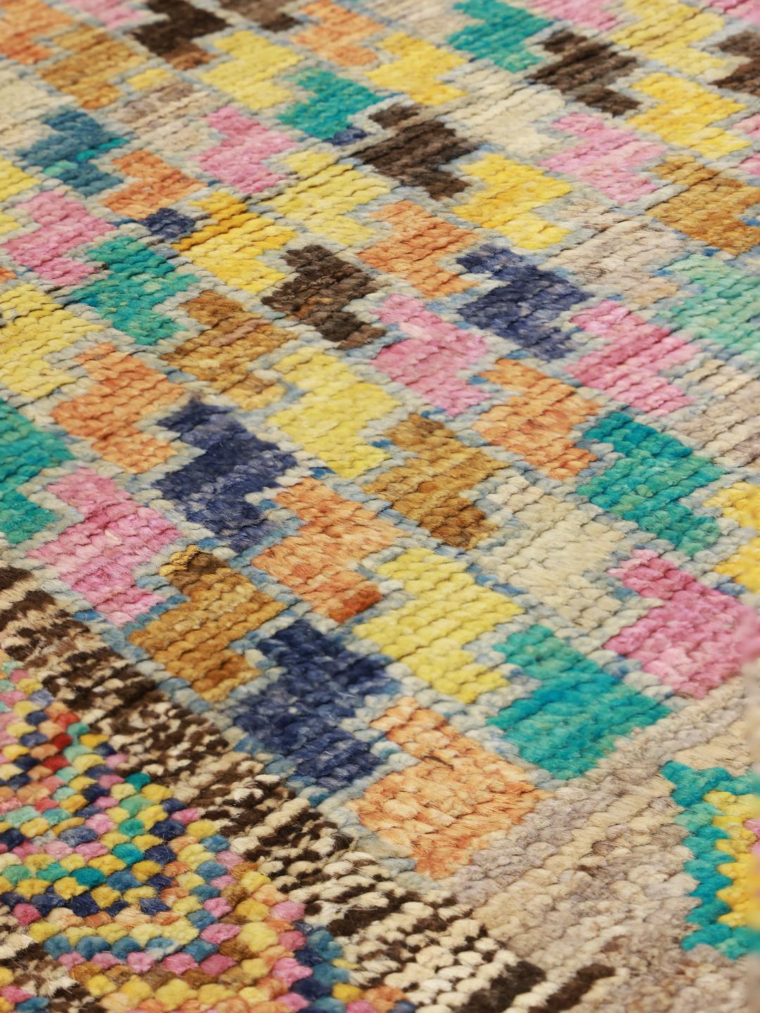 Een levendig, met de hand geknoopt wollen tapijt uit Afghanistan met kleurrijke geometrische patronen.