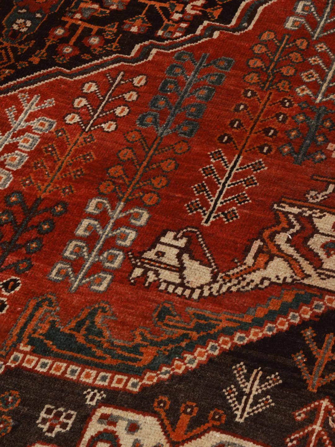 Hand-knotted Ghashghai rug from the Middle East featuring a red and black tribal pattern.