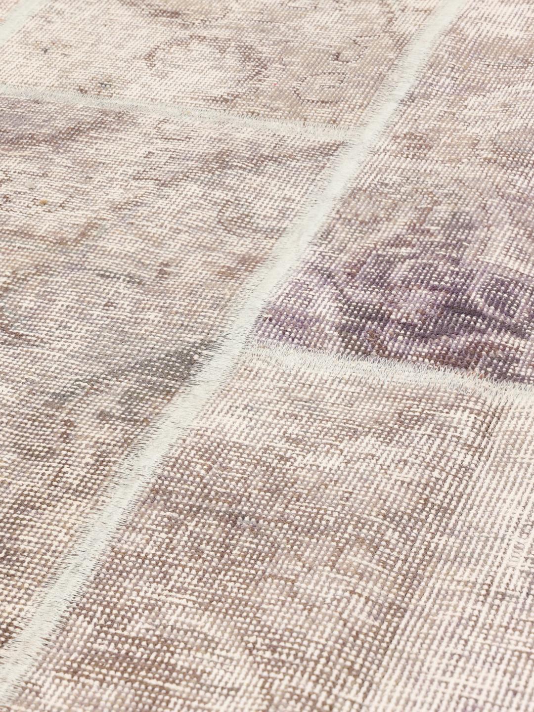 Et unikt patchwork-tæppe med lyse-lilla og neutrale toner, håndlavet i Mellemøsten.