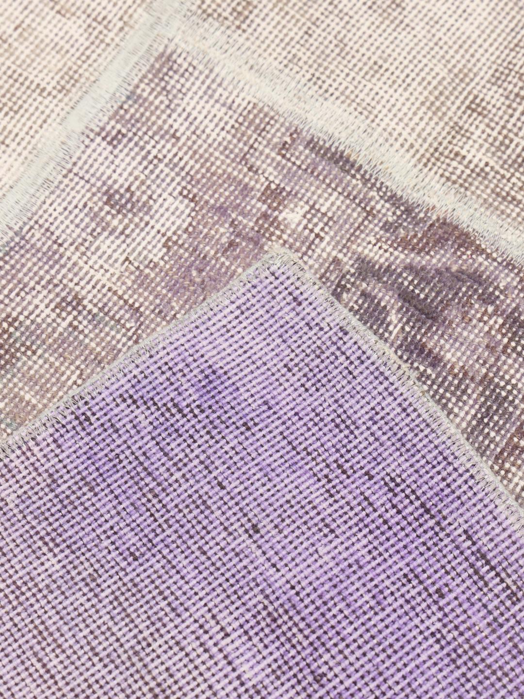 Et unikt patchwork-tæppe med lyse-lilla og neutrale toner, håndlavet i Mellemøsten.