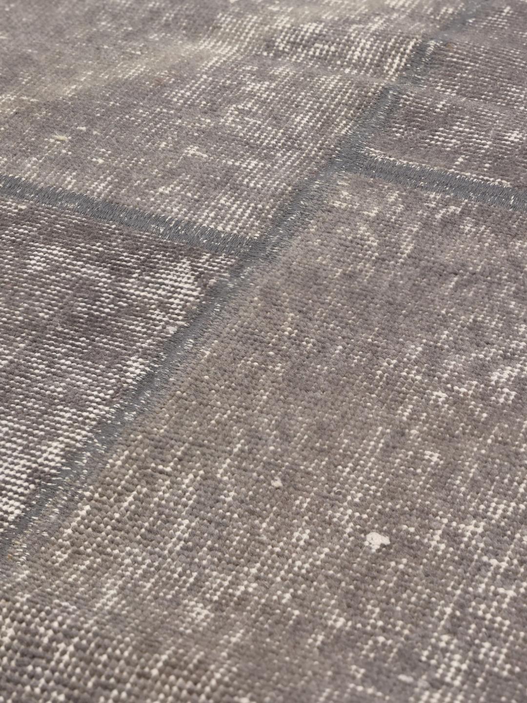 Et rektangulært patchwork-tæppe fra Mellemøsten i forskellige nuancer af mørkegrå.