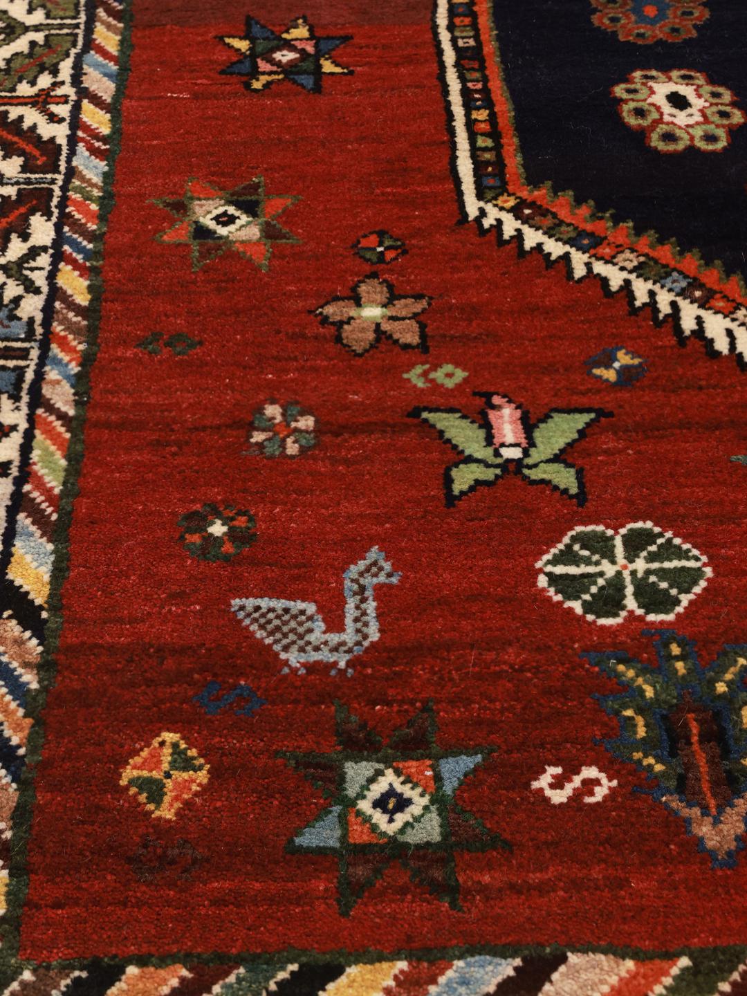 Hand-knotted Ghashghai rug from the Middle East featuring a red and dark blue colour palette