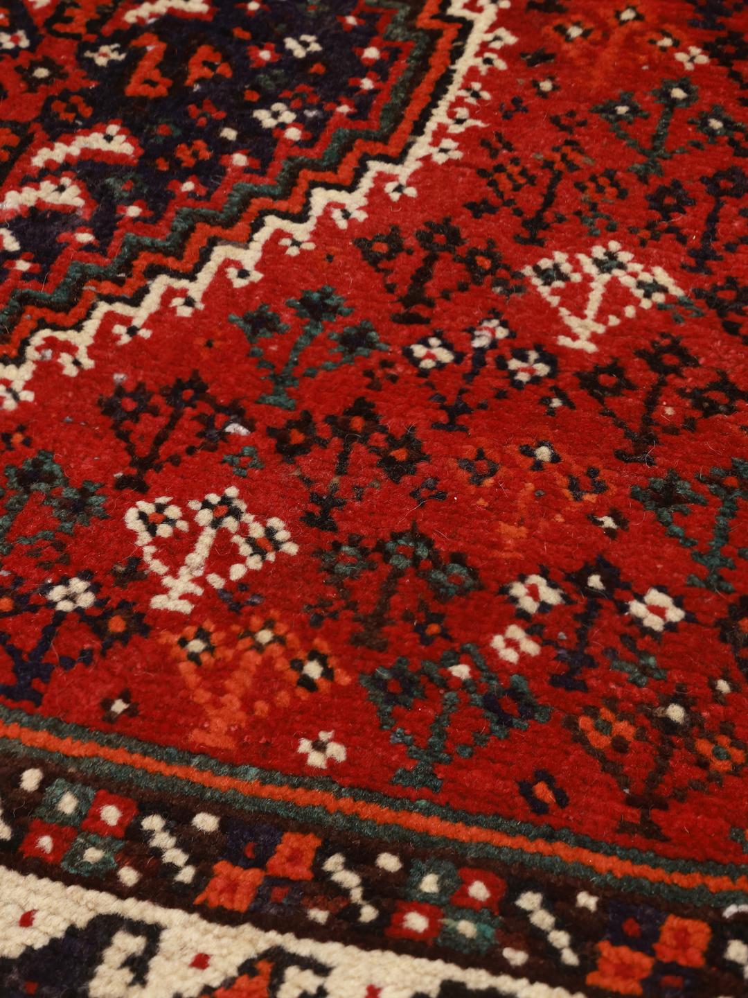 A hand-knotted Shiraz rug from the Middle East in deep red with geometric patterns.