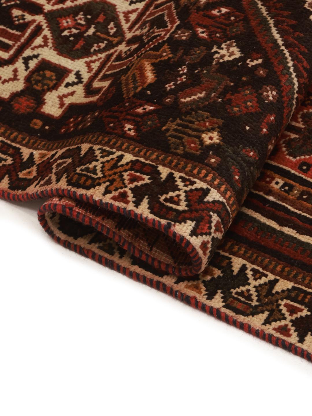 A hand-knotted Qashqai rug from the Middle East featuring a red field and decorative borders.