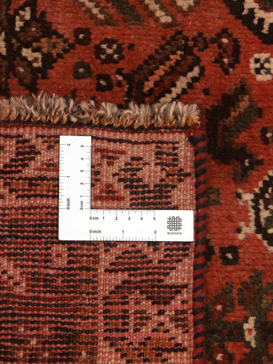 A hand-knotted Qashqai rug from the Middle East featuring a red field and decorative borders.
