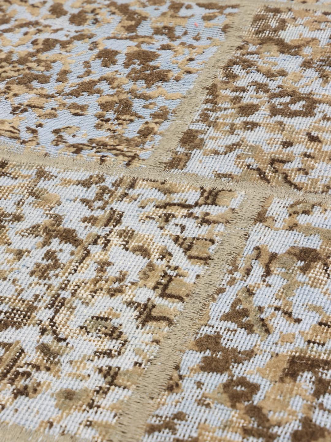 Et rektangulært patchwork-tæppe fra Mellemøsten med en blanding af beige og lyseblå toner.
