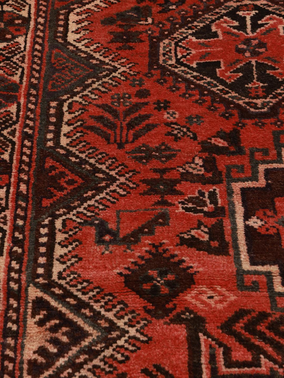 A hand-knotted Shiraz rug from the Middle East featuring geometric red patterns.