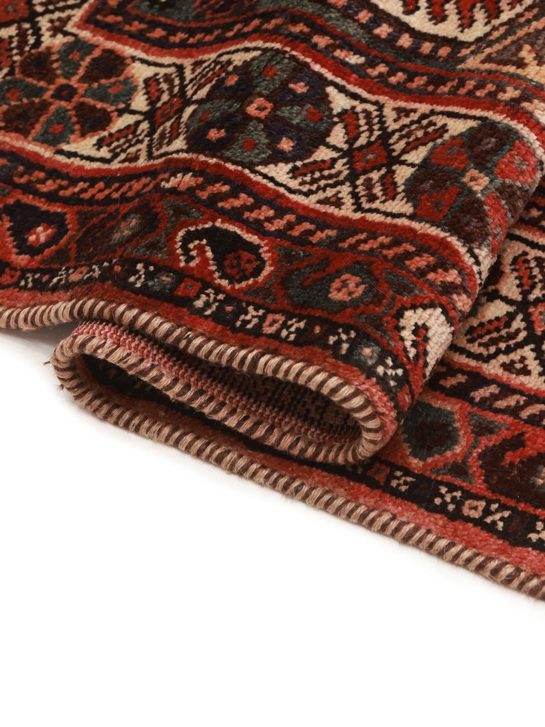 A hand-knotted Shiraz rug from the Middle East featuring geometric red patterns.