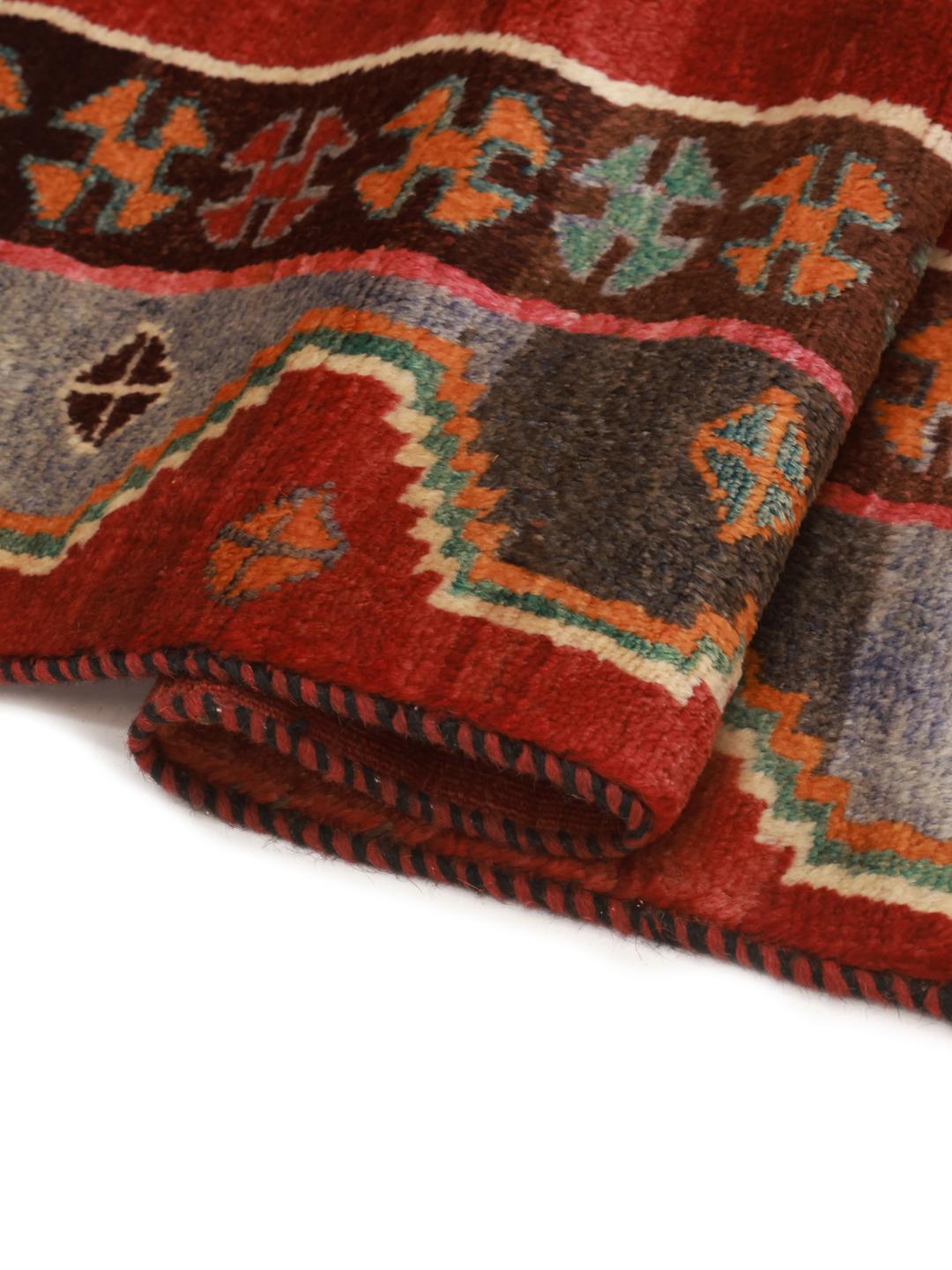 A hand-knotted Ghashghai rug from the Middle East with a vibrant red field and geometric patterns.