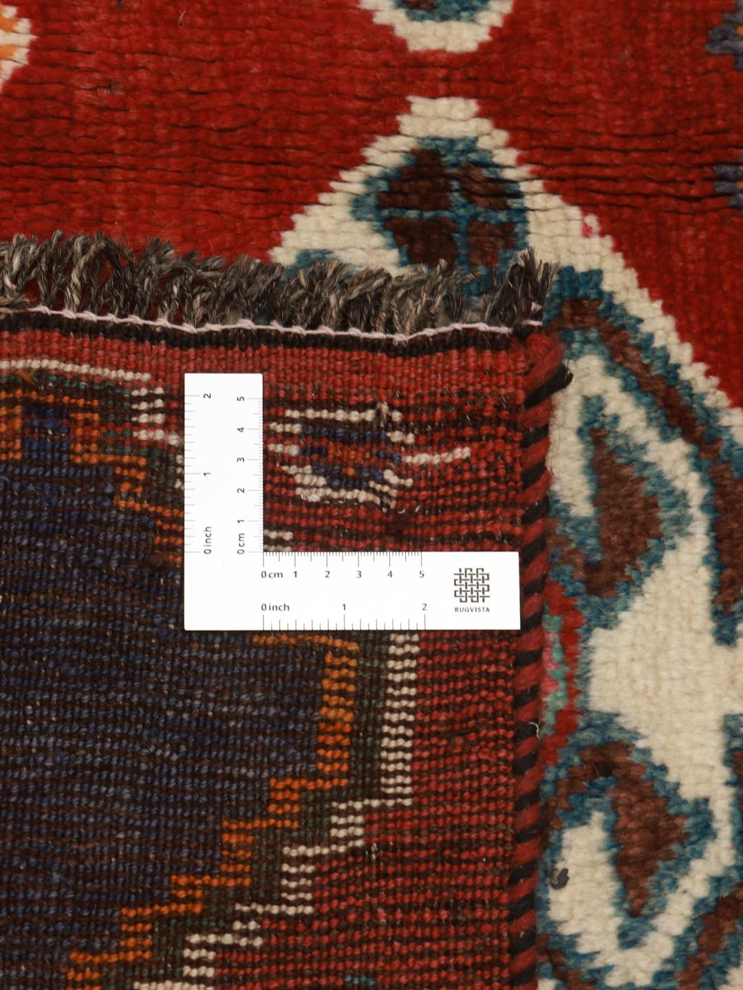 A hand-knotted Ghashghai rug from the Middle East with a vibrant red field and geometric patterns.