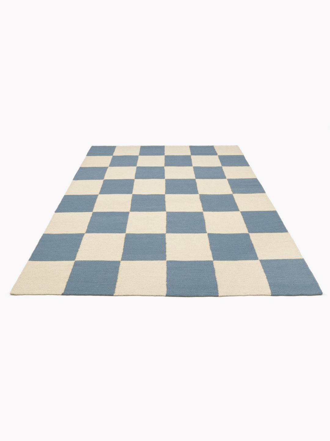 Een handgeweven wollen tapijt in blauw en wit met een dambordpatroon.